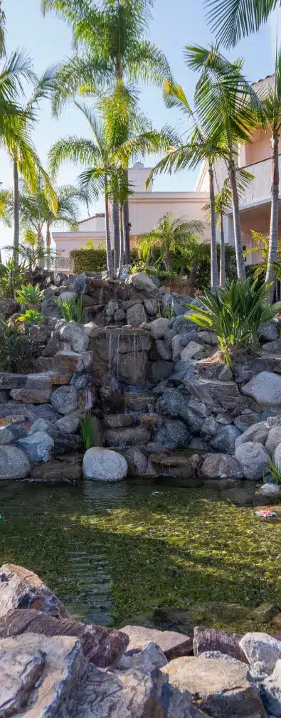 Rock waterfall and pond surrounded by palm trees at Villa Oasis
