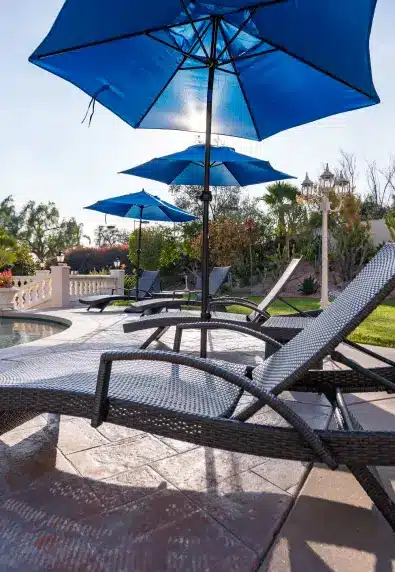 Lounge chairs and blue umbrellas on the pool terrace at Villa Oasis